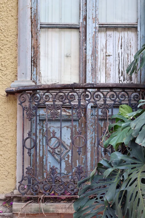 Balcón de herrería antigua sobre una fachada de madera desgastada