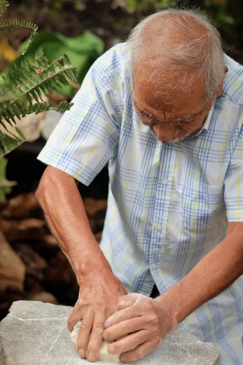 Manos de un cantero mayor trabajando un molcajete de piedra