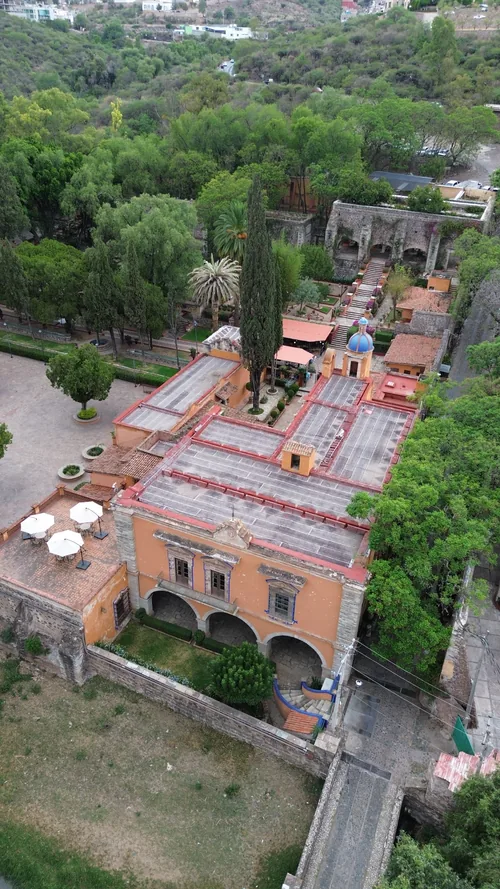 Vista aérea de una hacienda con techumbre de teja entre arboleda