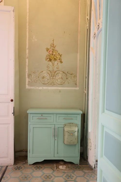 Habitación con muros claros y un mueble antiguo color menta