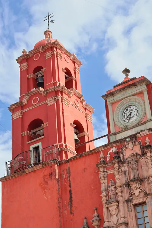 Torres de un templo pintado de rojo con reloj
